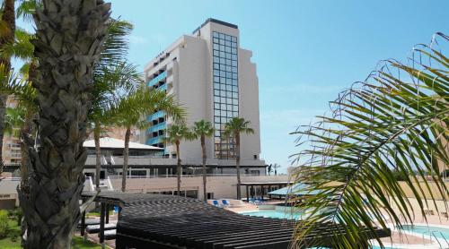 un complejo con una palmera y un edificio en 4Us LA MANGA VIP HOTEL en La Manga del Mar Menor