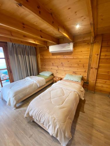 two beds in a room with wooden walls at كوخ السحاب in Al Hada
