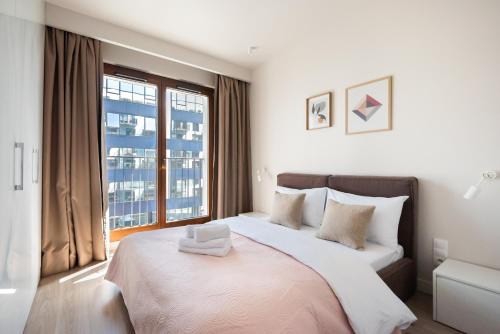- une chambre avec un grand lit et une grande fenêtre dans l'établissement Magazynowa Classy Apartment, à Varsovie