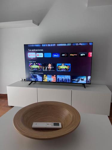 TV de pantalla plana en un soporte blanco con mando a distancia en Casa de Fernando, en Puerto Real