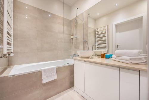La salle de bains est pourvue d'une baignoire, d'un lavabo et d'une douche. dans l'établissement Magazynowa Classy Apartment, à Varsovie
