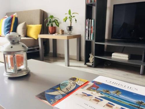 una sala de estar con una mesa con un libro y una linterna en Apartment Cristo de la Epidemia Malaga by SharingCo, en Málaga