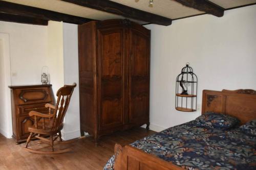 um quarto com uma cama, um armário de madeira e uma cadeira em Le hameau de Donnedevie em Marcillac-la-Croisille