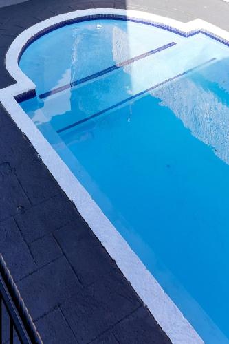 a swimming pool with blue water and a fence at Airport Royal Guest House in Kempton Park