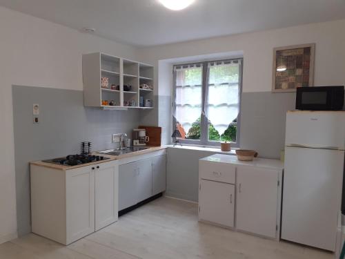 uma cozinha com armários brancos e um frigorífico branco em Les chênes blancs em Aubin