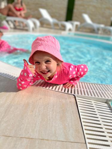 a little girl in a pink hat is in a swimming pool at Готель-спа "Еліт" in Kolʼchyno