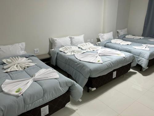 three beds in a room with towels on them at Hotel Beirut in Aparecida