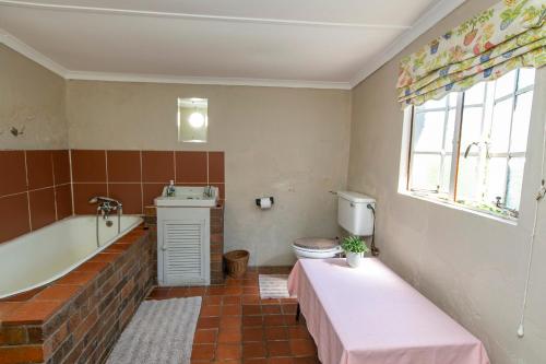 ein Badezimmer mit einer Badewanne, einem WC und einem Waschbecken in der Unterkunft Ripon Country Cottage in Himeville