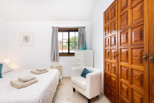 1 dormitorio con 2 camas y una silla blanca en CASA BRANSFORD, Excellent, Sunny House with Private Heated Pool, en San Miguel de Abona