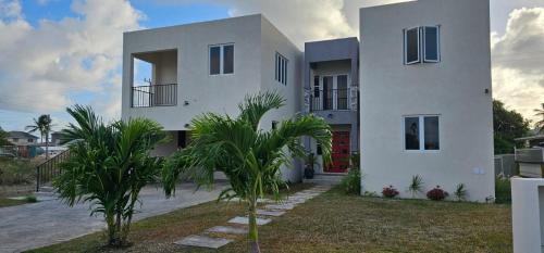 a white house with palm trees in front of it at 03Villa in Christ Church