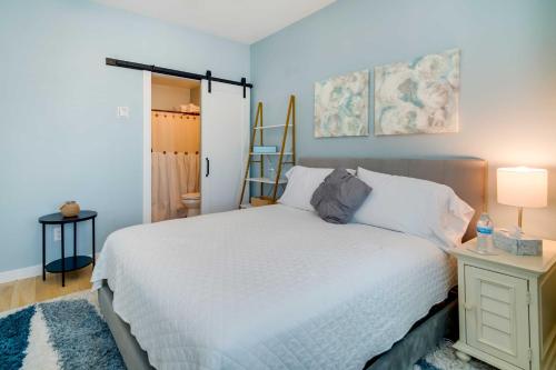 een slaapkamer met een wit bed en een tafel met een lamp bij Modern Ocean City Getaway Walk to Boardwalk! in Ocean City