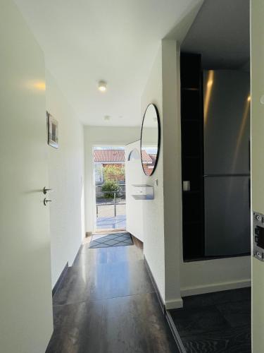 a hallway with white walls and a mirror at aday - Elegant Apartment with Terrace in Svenstrup