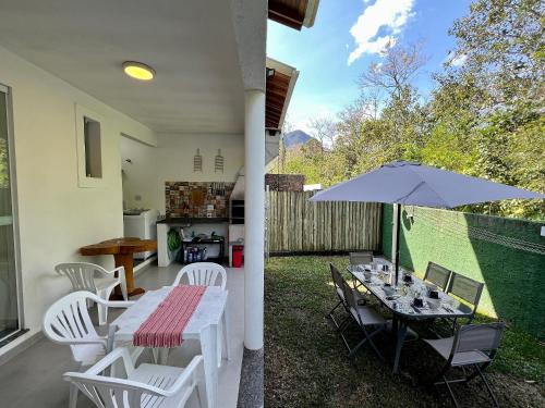 eine Terrasse mit einem Tisch und einem Sonnenschirm in der Unterkunft Casa Clean e Comfort, a mais completa de Paúba in São Sebastião