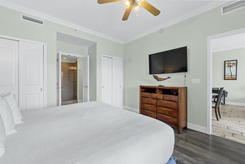 a white bedroom with a bed and a flat screen tv at Reflections by Panhandle Getaways in Panama City Beach