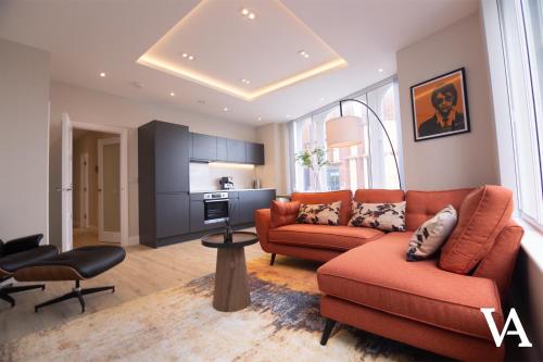 a living room with orange furniture and a kitchen at Velvet Apartments - 56 Vicar Lane in Leeds