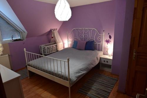 1 dormitorio con cuna blanca y paredes moradas en Balaton Soul House, en Vonyarcvashegy