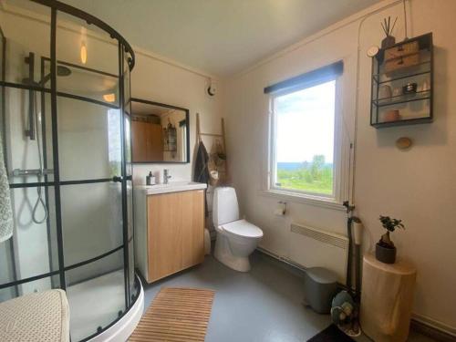 a bathroom with a shower and a toilet and a window at Forest cabin with stunning mountain view & Sauna in Torsby