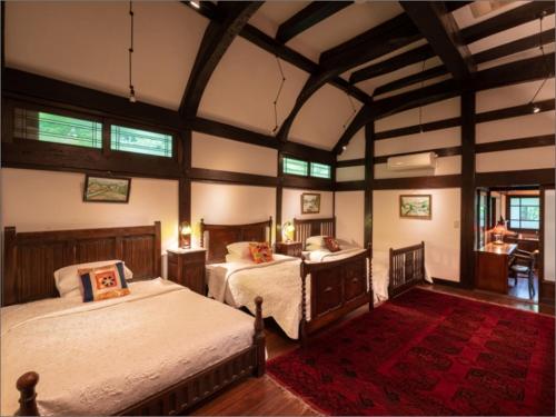 - une grande chambre avec 2 lits et un tapis rouge dans l'établissement Nihon-no-Ashitaba, à Yufu