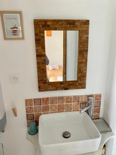 une salle de bain avec un lavabo et un miroir dans l'établissement La Charmette, à Sète