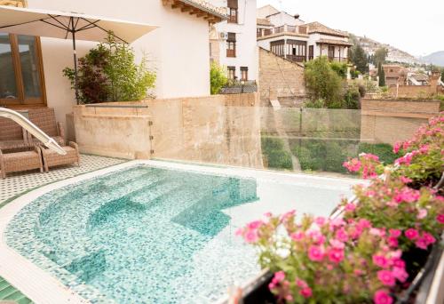 a swimming pool in front of a house with flowers at La Corrala del Realejo in Granada