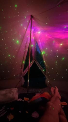 una persona en una habitación con techo púrpura y verde en Stargazer bell tent secret garden glamping, 
