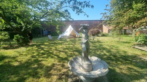 a statue of a woman in a yard with a tent at Stargazer bell tent secret garden glamping 