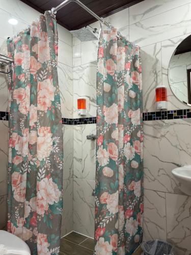 a bathroom with a shower with a floral shower curtain at Cabinas Vista Al Golfo in Monteverde Costa Rica