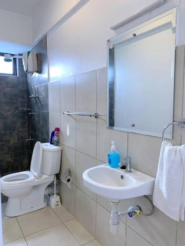 a white bathroom with a toilet and a sink at Modern 1-Bedroom Unit 5 mins from CBD in Nairobi