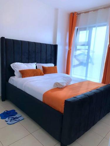 Cama azul con manta naranja y ventana en Modern 1-Bedroom Unit 5 mins from CBD en Nairobi