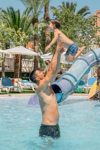 a man and a child jumping off a water slide in a pool at Magic Tropical Splash in Cala de Finestrat
