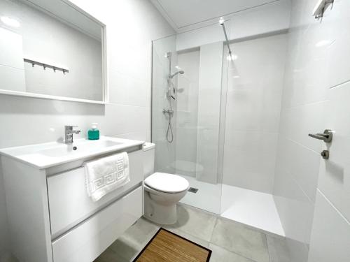 a white bathroom with a toilet and a shower at Holiday Beach Apartment in Denia