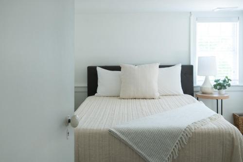 a white bedroom with a large bed with white pillows at The Carriage House at Strasburg in Strasburg