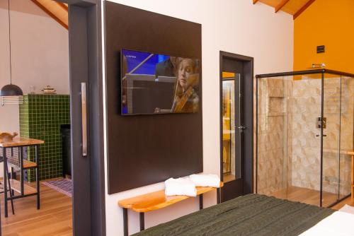 a bathroom with a television on a wall at Timber Lodge Camanducaia in Monte Verde