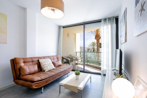 a living room with a leather couch and a balcony at Apartment Carmen Sunrise, Los Cristianos in Los Cristianos