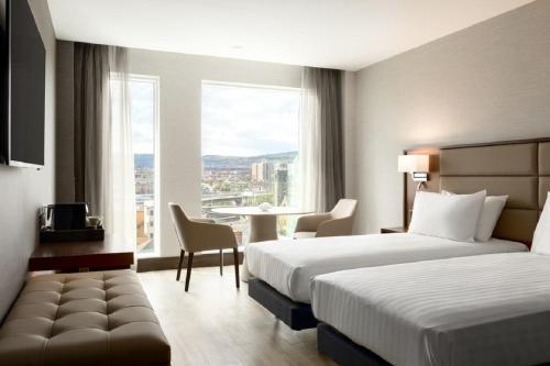 a hotel room with two beds and a table at AC Hotel by Marriott Belfast in Belfast