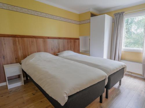 two beds in a bedroom with yellow walls and a window at Selmas Gård in Östra Ämtervik