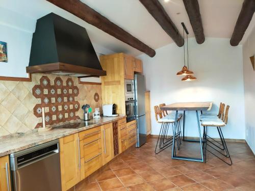 een keuken met houten kasten en een tafel met krukken bij Casa Cuatro Vientos in Tordera