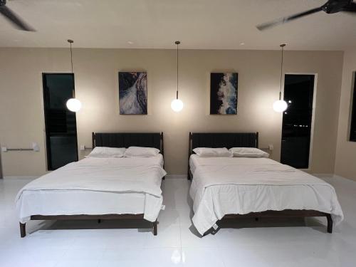 two beds in a room with white sheets and lights at Eleven8 Taman Pandan in Alor Setar