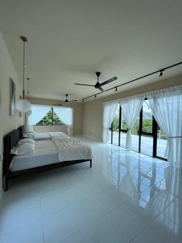 a white bedroom with a bed and a ceiling fan at Eleven8 Taman Pandan in Alor Setar