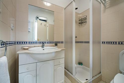 a white bathroom with a sink and a shower at Casa Alto do Perogil Tavira-3 bedroom house with pool & free wifi in Tavira