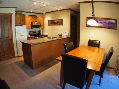 a kitchen with a wooden table and a dining room at Fireside Lodge #409 By Bear Country in Sun Peaks