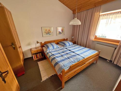 a bedroom with a bed with a blue comforter and a window at Ferienwohnung Wagner in Bergen
