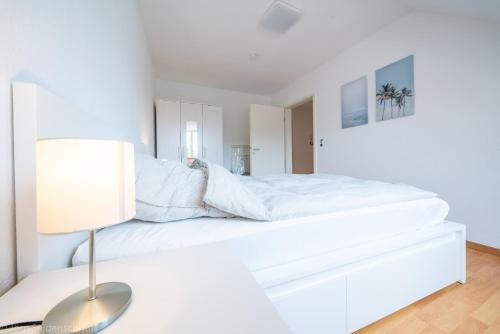 Un dormitorio blanco con una cama blanca y una lámpara en Edle DG Maisonette mit Balkon, Wohnzimmer, Arbeitszimmer, Waschmaschine, Top Ausstattung, zentral, en Fürstenwalde