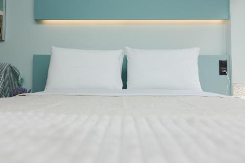 Una cama blanca con almohadas blancas encima. en EllMar - new & modern studio in the center, en Chalkida