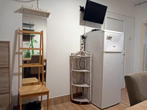 a kitchen with a refrigerator and a tv on a wall at Studio apartment Novi Sad in Novi Sad