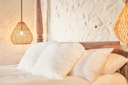a bed with white pillows and a hanging lamp at The Aerial, BVI in Tortola Island