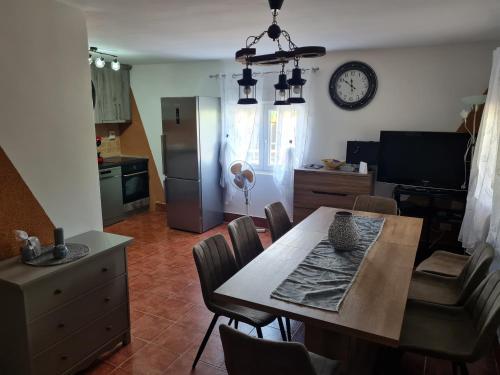 eine Küche und ein Esszimmer mit einem Tisch und einer Uhr in der Unterkunft Vila Tea Fruska Gora in Čortanovci