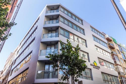 um prédio de apartamentos com uma árvore em frente em Lemon & Soul Las Palmas em Las Palmas de Gran Canaria