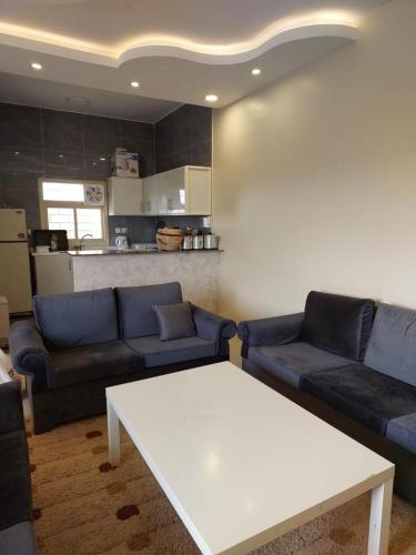 ein Wohnzimmer mit blauen Sofas und einem weißen Tisch in der Unterkunft استراحة في منطقة مرتفعة بالقرب من أبها in Abha