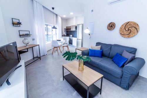 Una sala de estar con un sofá azul y una mesa. en Bex Holiday Homes, en Las Palmas de Gran Canaria